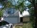 1983 Ford 427 - A white sedan is parked in the driveway of a house with a stone facade and a two-car garage.
