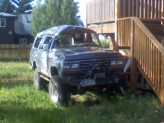 Toyota Land Cruiser with lifted suspension and winch, parked next to a wooden deck