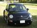 1999 Volkswagen Beetle - A black Volkswagen Beetle is parked outdoors on a grassy area with trees in the background.