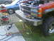 1984 Chevrolet Blazer - A red truck with a custom metal bumper and its hood open, parked next to a blue sedan.