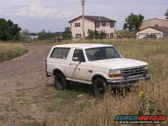 white Ford Bronco parked on gravel road near a house
