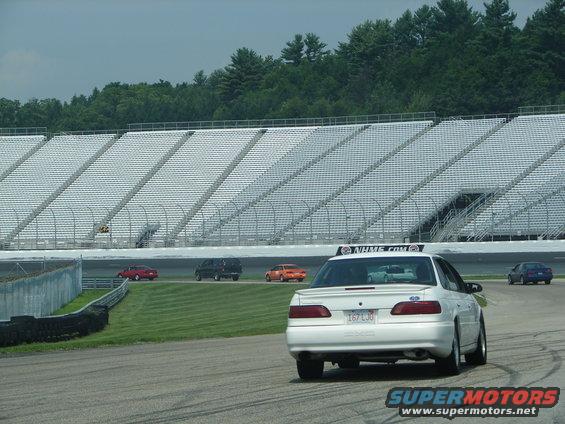 White 1992 Ford Taurus sedan from rear, on a race track with grandstands