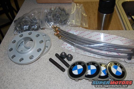 BMW wheel spacers, lug bolts, and center caps laid out on a counter