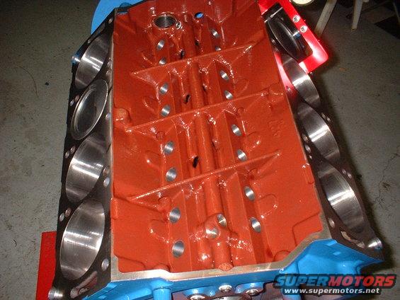 Engine block with orange paint and blue accents, showing cylinder bores and internal structure