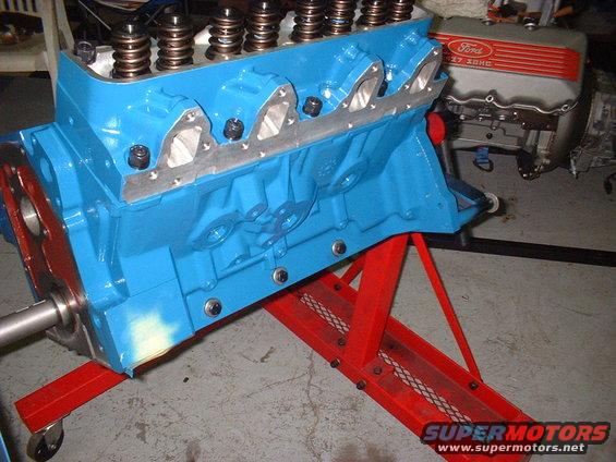 Blue painted engine block on red stand, with another engine in background showing Ford 272 2V logo