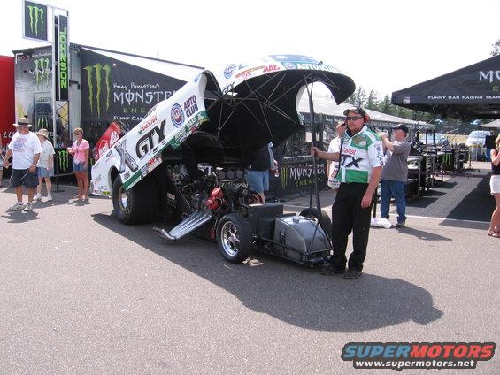 Funny car drag racer with hood open, showing engine. Monster Energy sponsorship visible