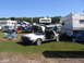1998 GMC Sierra 1500 - A silver DeLorean DMC-12 is parked in a grassy field with several RVs and tents visible.