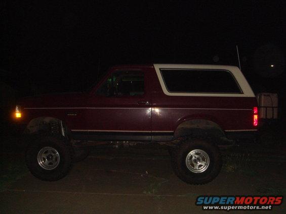 Side view of a red 1992 Ford Bronco with a white top