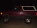 1992 Ford Bronco - Side view of a lifted 1992 Ford Bronco with a two-tone paint scheme, photographed after dark.