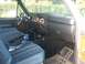 1982 Ford Bronco - The interior of a truck cab features blue plaid seats and a dashboard with wood grain accents.