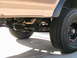 1985 Ford Bronco - The underside of a vehicle shows its suspension components and off-road tires.