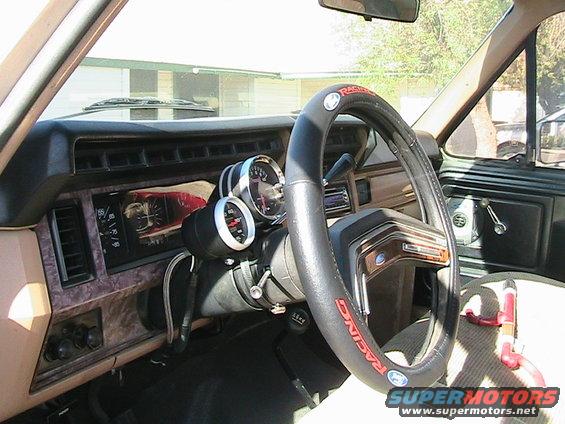 Interior view of a vehicle with aftermarket gauges and a racing steering wheel cover