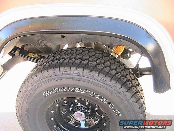 Close-up of a vehicle's rear tire, suspension, and wheel well. Tire is Goodyear brand