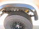 1985 Ford Bronco - The rear suspension and tire of a vehicle are visible, with a yellow shock absorber.