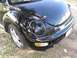 1999 Volkswagen Beetle - A black Volkswagen Beetle is viewed from the front quarter, revealing its distinctive rounded headlights and fender emblem.