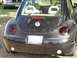 1999 Volkswagen Beetle - Rear view of a black 1999 Volkswagen Beetle parked outdoors with another car in the background.