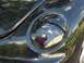 1999 Volkswagen Beetle - Close-up of a black car's headlight assembly, showing reflections of the surrounding environment.