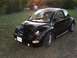 1999 Volkswagen Beetle - This black Volkswagen Beetle is parked outdoors on a grassy area during sunset.