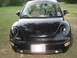 1999 Volkswagen Beetle - This black Volkswagen Beetle is parked outdoors on a grassy area. The front of the car is visible, including the headlights and license pla…