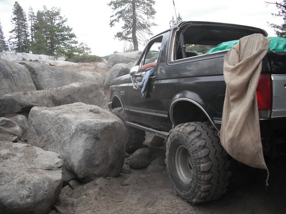 Black Ford Bronco navigating large rocks on a dirt trail