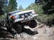 1991 Ford Bronco - Ford Bronco tackling a challenging off-road trail with its front wheel lifted.