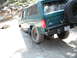 1991 Ford Bronco - This green Ford Bronco is navigating a dirt path with its spare tire visible on the rear.