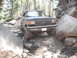 1991 Ford Bronco - This Ford truck is shown on a challenging off-road trail surrounded by trees and large rocks.
