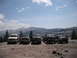 1991 Ford Bronco - A group of off-road trucks are parked on a rocky terrain with a mountainous landscape under a partly cloudy sky.