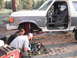 1991 Ford Bronco - Two people are working on the suspension and brakes of a 1991 Ford Bronco outdoors.