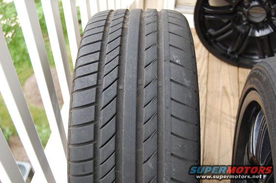 Close-up of a tire tread with a black wheel in the background