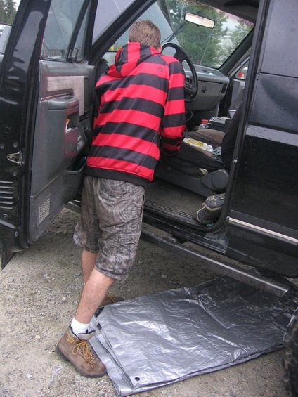 Guy in a red and black striped hoodie gets into a black truck