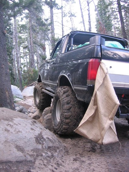 Black 1987 Ford Bronco on rocky trail, rear 3/4 view