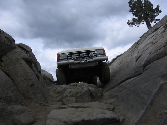 White 1989 Ford Bronco navigating a rocky trail