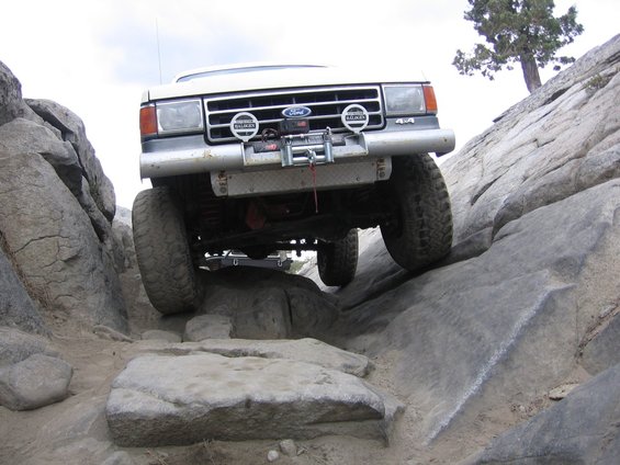 Ford Bronco climbing over rocks on a trail. Has a winch on the front bumper