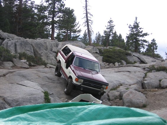 1989 Ford Bronco climbing over large rocks on a trail
