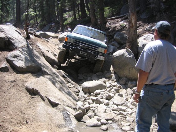Green 1989 Ford Bronco navigating a rocky off-road trail