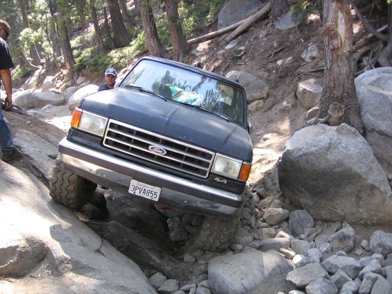 Black Ford Bronco navigating a rocky trail, front view. The vehicle has a California license plate reading 3PVA855 and a 4x4 badge