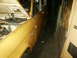 1966 Ford Bronco - The side of a yellow Ford Bronco is visible, with the hood open, in a dimly lit indoor space.