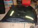 1992 Ford Taurus - A detached car hood with significant paint damage rests on supports in a workshop.