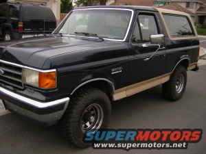 Black Ford Bronco with tan top, 3/4 front view, showing chrome bumper and alloy wheels