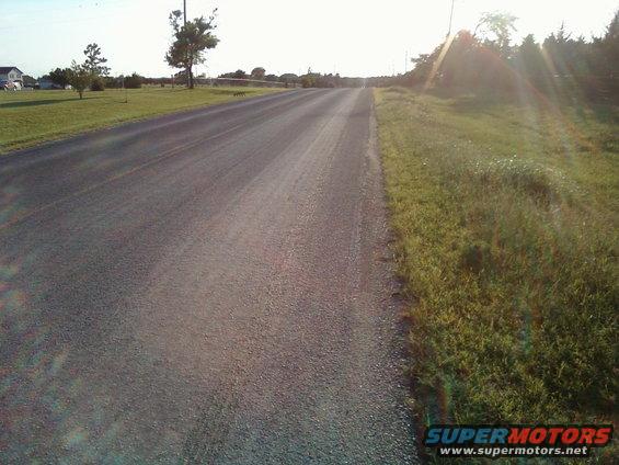 empty two-lane road in a rural area with grass and trees on the side