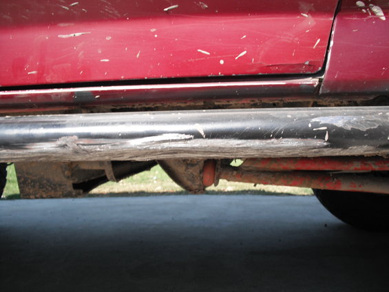 Red vehicle side with black running boards and visible suspension parts