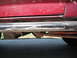 1991 Ford Bronco - Close-up view of the lower side panel and running boards of a red vehicle, showing suspension components underneath.