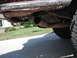 1991 Ford Bronco - The underside of a vehicle shows mud accumulation and a worn exhaust system.