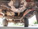 1991 Ford Bronco - The underside of a vehicle reveals its complex mechanical components and heavy-duty suspension system.