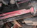 1991 Ford Bronco - Close-up view of the undercarriage, highlighting red suspension parts and various mechanical components.