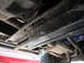 1991 Ford Bronco - The undercarriage of a vehicle shows its frame, exhaust system, and a portion of a tire.