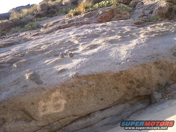 RC crawler toy truck on a large rock with desert plants in background