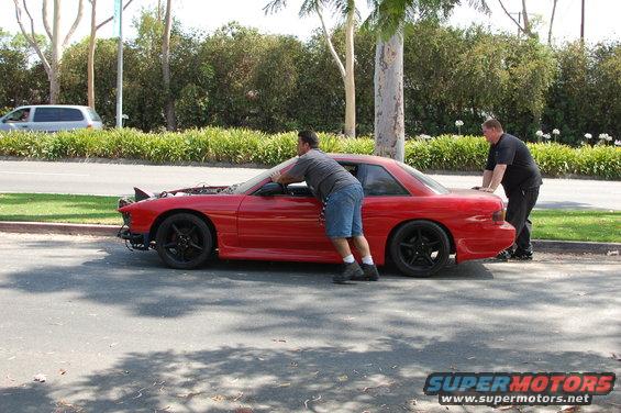 1991 Nissan 240SX coupe with hood open, two men pushing it on the side of the road