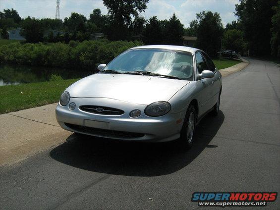 Silver sedan parked on the side of a road, front 3/4 view